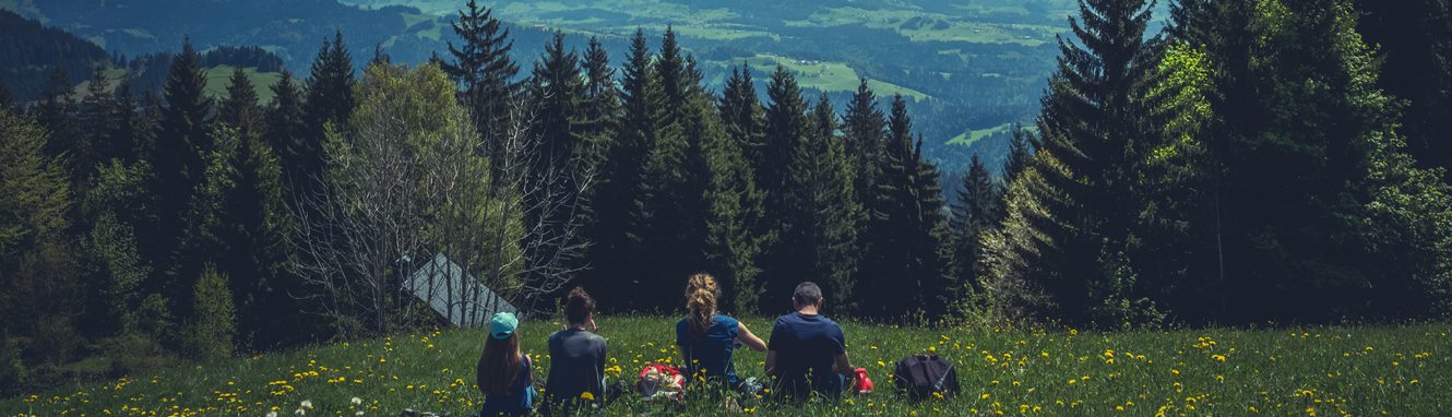 Family sitting in the grass with a view of the mountains.